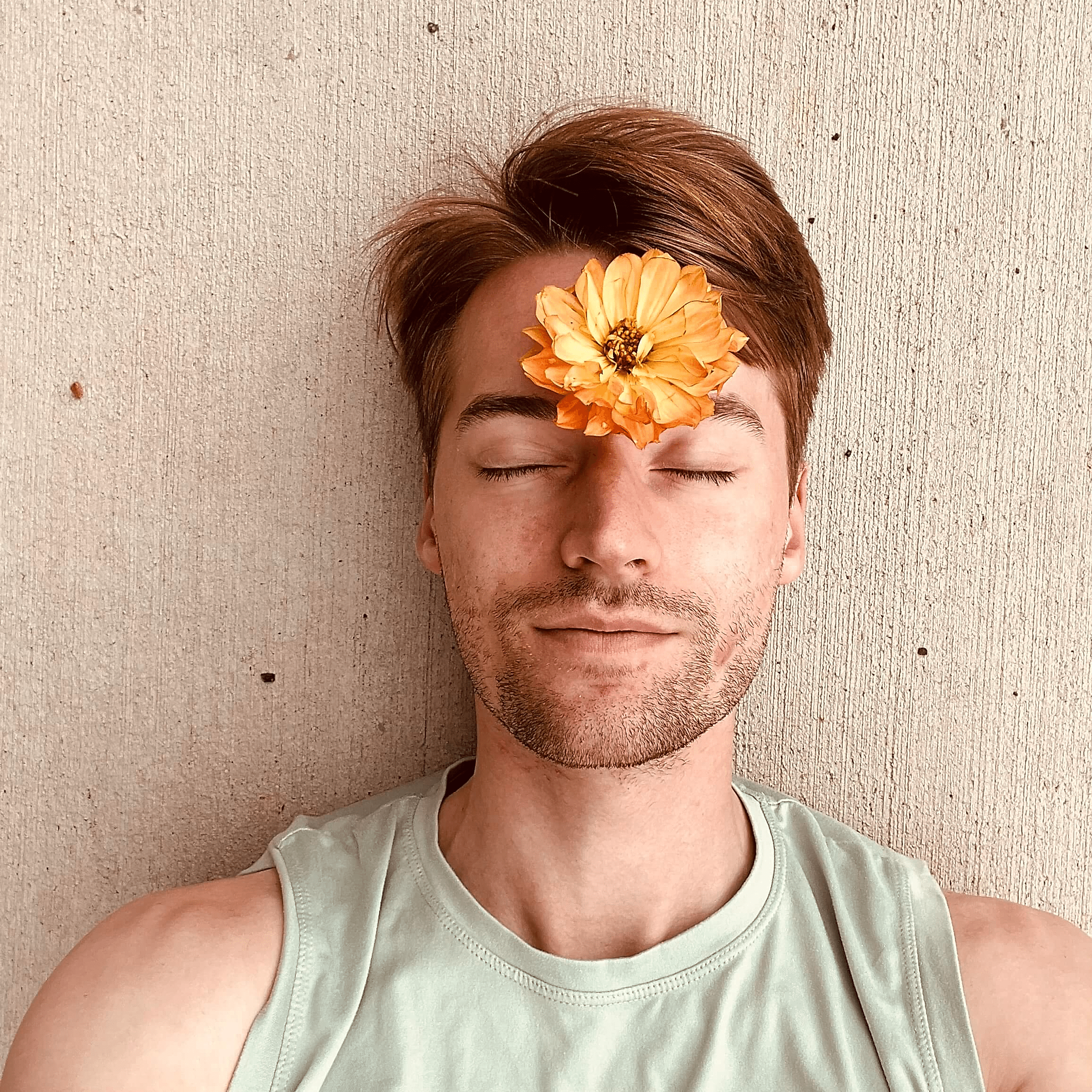 Photo of Caleb laying down with a flower on their forehead